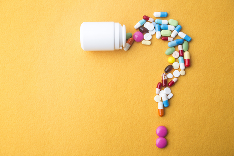 Pill bottle with pills shaped into question mark Pill bottle with pills shaped into question mark