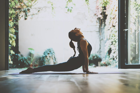 yoga instructor // Photo by Pinkypills/iStock/Getty Images Plus/Getty Images yoga instructor stretching in front of a garden