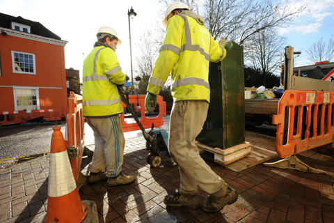 Fiber install two utility workers setting up a fiber cabinet on a sidewalk