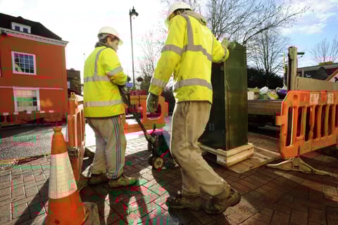 Fiber install two utility workers setting up a fiber cabinet on a sidewalk