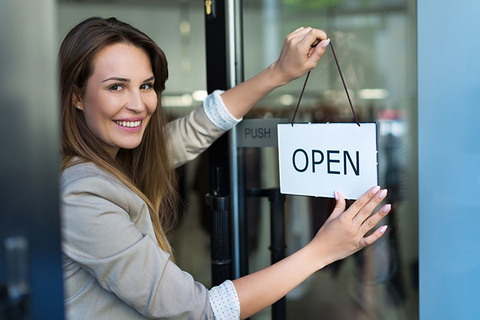 Small Business Owner Getty Woman hanging an open sign on a small business