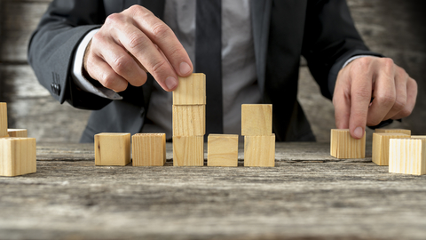 Building blocks man in suit stacking blocks