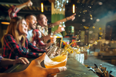 Guests celebrating in a sports bar and spilling beer Person spilling beer celebrating at a sports bar