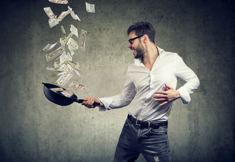 Man flipping money in a frying pan Man tossing money in a frying pan