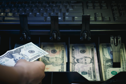 Cash register full of money Hand reaching into or pulling out of cash register
