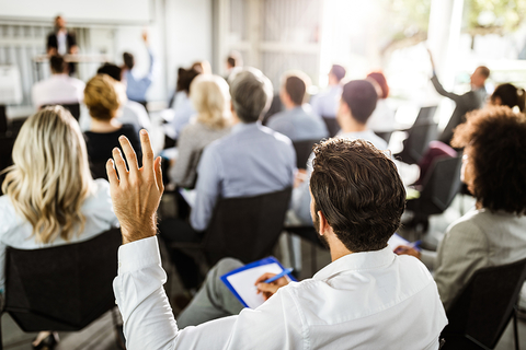 Conference Stock Photo A man raises his hand at a conference.