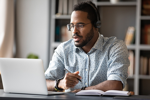 man on laptop with headphones - studying - webinar - training man on laptop with headphones