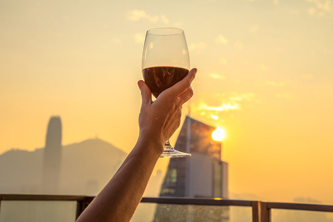 Hong Kong Rooftop Bar Getty Close up of glass of red wine raised with the background the spectacular Hong Kong skyline at sunset.