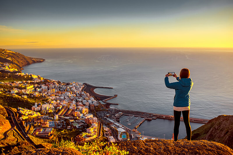 Woman taking photo of Santa Cruz on smartphone - RossHelen/iStock/Getty Images Plus/Getty Images Woman taking photo of Santa Cruz on smartphone