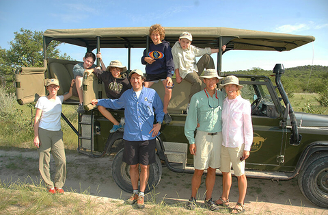 Natural Habitat Adventures // Photo by Natural Habitat Adventures Family on safari standing in front of a 4x4 SUV
