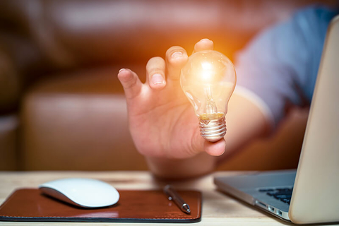man holding lightbulb next to laptop // Photo by PhotoBylove/iStock/Getty Images Plus/Getty Images man holding lightbulb next to laptop