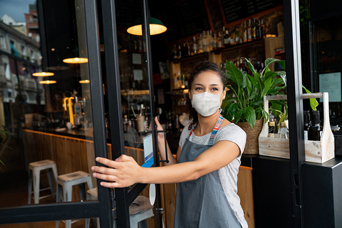 Woman wearing mask, opening door to restaurant Woman wearing mask, opening door to restaurant