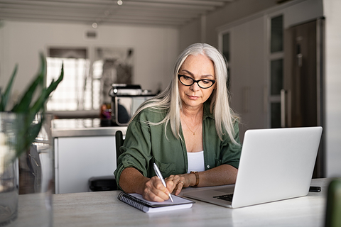 woman taking notes and using laptop woman taking notes and using laptop