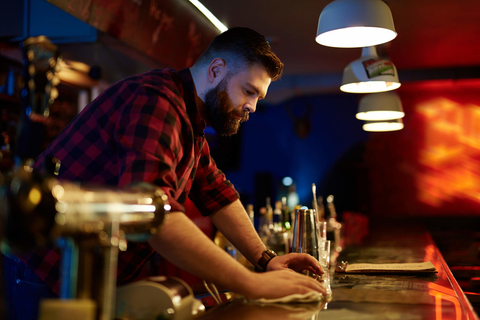 Bearded bartender wiping down bar Bearded barman cleaning bar