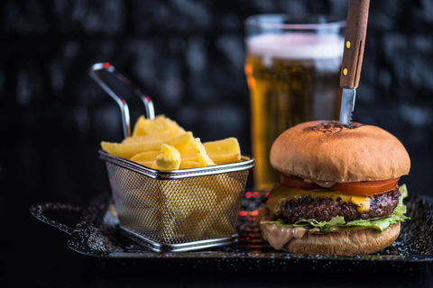French fries, burger with knife through it and beer Burger with knife, French fries and beer