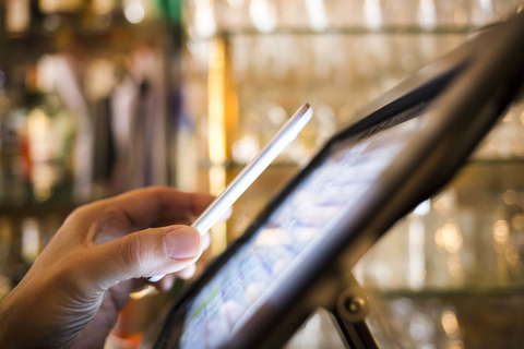 Person paying in bar or restaurant with NCF technology Person paying tab at bar or restaurant with cell phone app