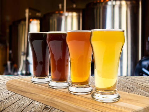 Four beers in front of tanks Beers in a brewery