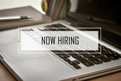 Notebook and laptop with NOW HIRING text NOW HIRING text over notebook and laptop