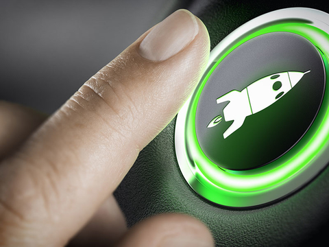Boost Button Getty Man finger pressing an boost button with a rocket icon, black background and green light