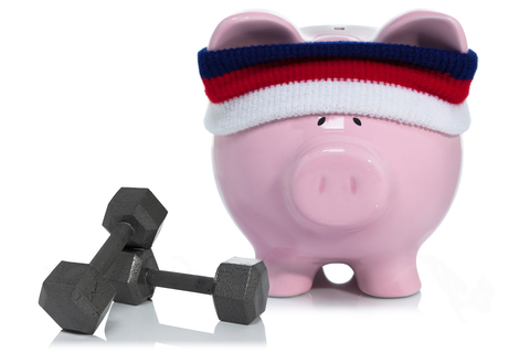 Building savings Pink piggy bank wearing sweatband with dumbbell weights