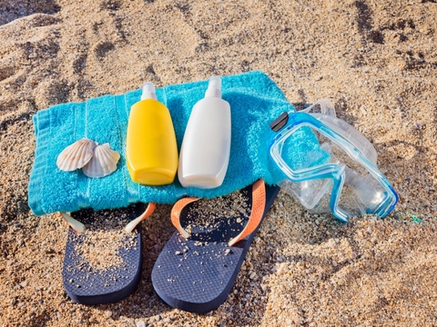 Sunscreen, slippers, swimming gear on the beach Beach vacation