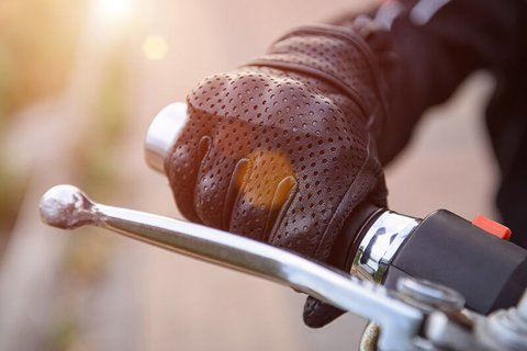 motorcycle // Photo by ninelutsk/iStock/Getty Images Plus/Getty Images a gloved handing holding the handle of a motorcycle