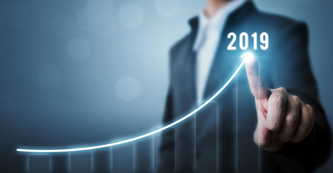 Businessperson pointing to graph showing growth for 2019 Data trending upward in 2019 on graph