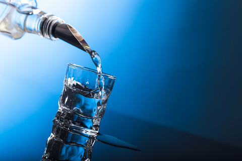 Clear alcohol being poured into glass Clear spirit pouring into a glass