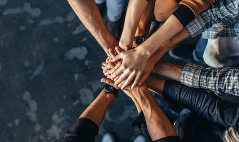 Symbol of teamwork, cooperation and unity Hands on top of hands symbolizing teamwork