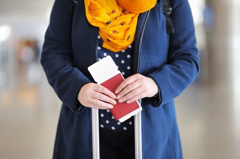 A woman holding a passport and plane ticket.
