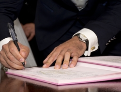 Man in suit signing his name to a book