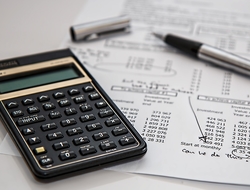 Calculator and pen on top of financial spreadsheet