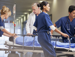 emergency doctor physician nurse patient gurney CREDIT: Getty/Sam Edwards Doctor and nurses wheeling patient in gurney through hospital corridor