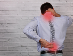 Back pain Back of man in long-sleeved shirt holding his neck and lower back. The places he's holding have red circles on them to indicate pain. An image of the spine is overlaid on his back.