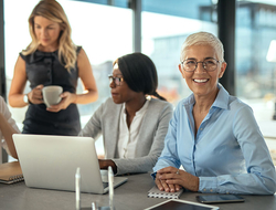 Older Worker Getty Group of female businesswomen working together on a laptop.