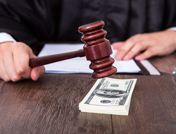 Court settlement Judge banging gavel on stack of money