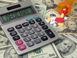 Medicare calculator with money Calculator that says "Medicare" on it on top of money, next to bottle of pills