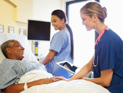 patient and nurse using tablet Nurse with tablet talking to senior woman in hospital bed