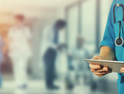 doctor with tablet photo shows torso of hospital doctor in hallway holding tablet computer