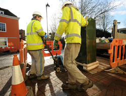 Fiber install two utility workers setting up a fiber cabinet on a sidewalk