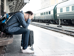 stressed traveler // Photo by ake1150sb/iStock/Getty Images Plus/Getty Images stressed traveler with head in hands outside at a train station