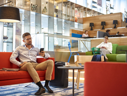 KLM non Schengen Crown Lounge Travelers sit on a colorful sitting area
