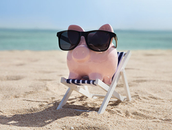 Summer Savings Vacation Beach Piggy Bank Getty Piggy bank wearing sunglasses on a beach